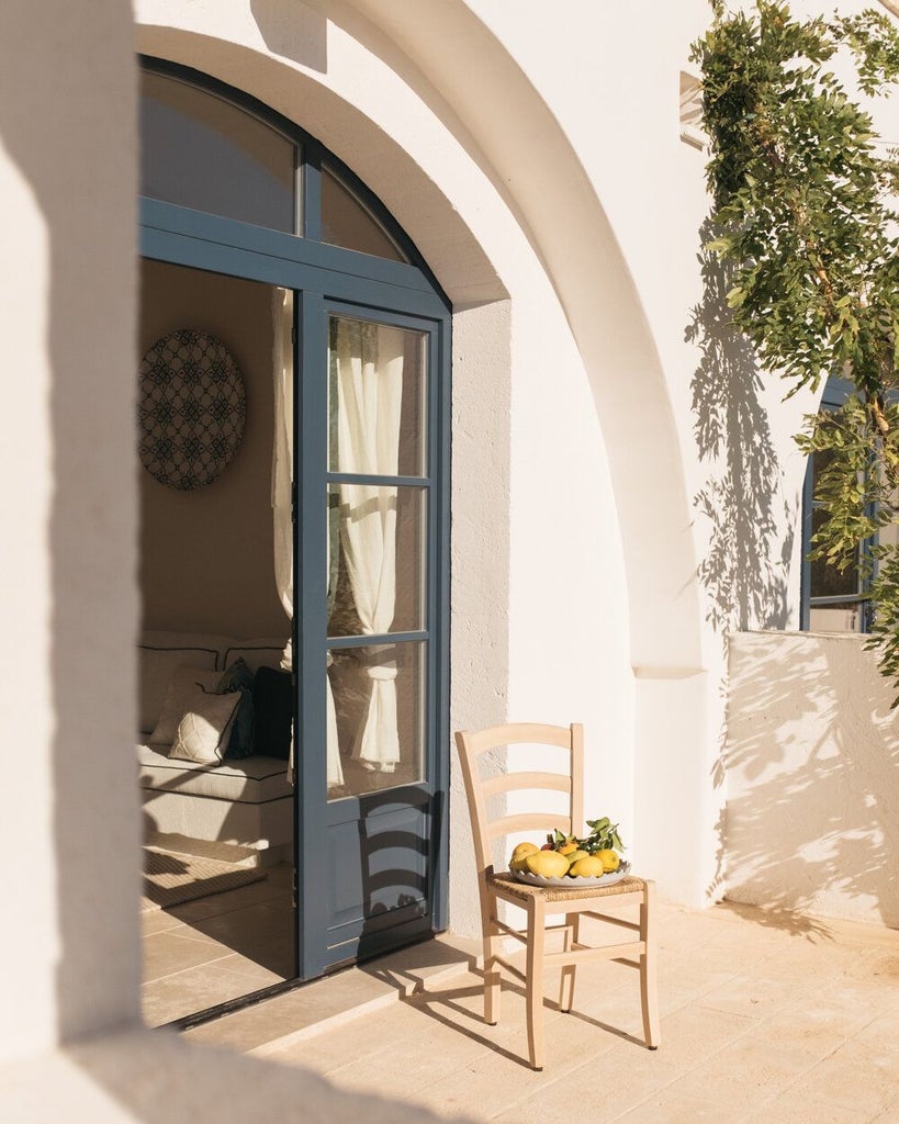 Rustic-chic stone villa nestled in Puglia's countryside, with sun-drenched terracotta roofs, azure Mediterranean backdrop, and lush olive grove surroundings