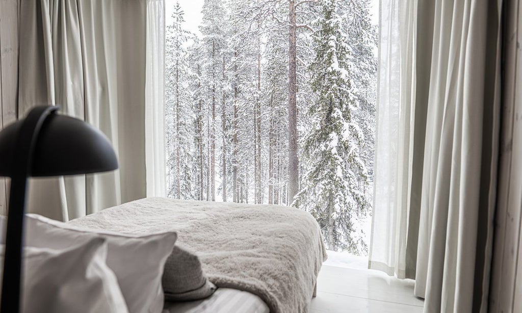 Luxurious Arctic TreeHouse Suite with panoramic windows, modern Nordic design, cozy fireplace, and stunning snow-covered forest view in Finland