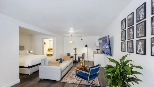 Elegant Argentine boutique hotel room with white linens, wooden furniture, warm lighting, and large windows overlooking a lush tropical garden landscape