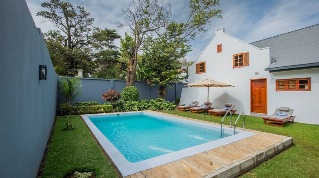 Elegant stone and thatch villa nestled in lush Tanzanian gardens, featuring infinity pool overlooking Mount Kilimanjaro at sunset