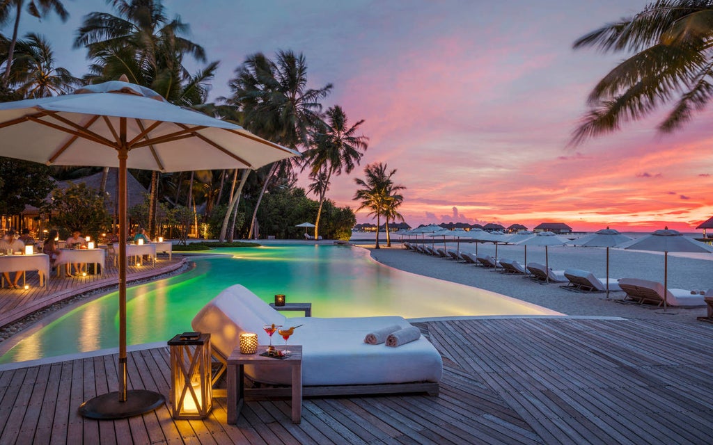 Luxurious overwater villa with private infinity pool extending over crystal-clear turquoise lagoon at sunset in Maldives