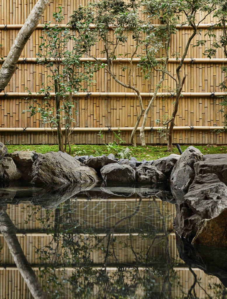 Traditional Japanese luxury pavilion at Aman Kyoto nestled among maple trees, with stone walkways and minimalist wooden architecture