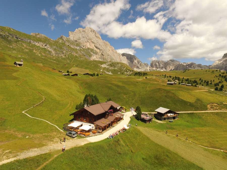 Modern mountain lodge with glass facade nestled in Italian Dolomites, featuring panoramic views of snow-capped peaks at sunset