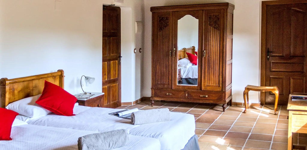 Elegant whitewashed Spanish villa room with rustic wooden furniture, soft linens, and a charming higuera (fig tree) view through large windows