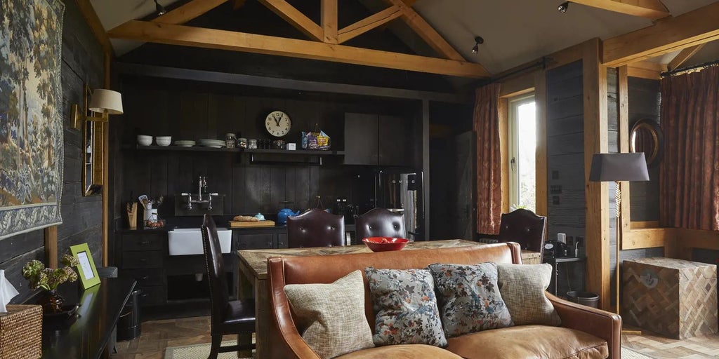 Rustic luxury forest cabin at Lime Wood, featuring warm wood paneling, plush bedding, and large windows overlooking lush woodland in the United Kingdom