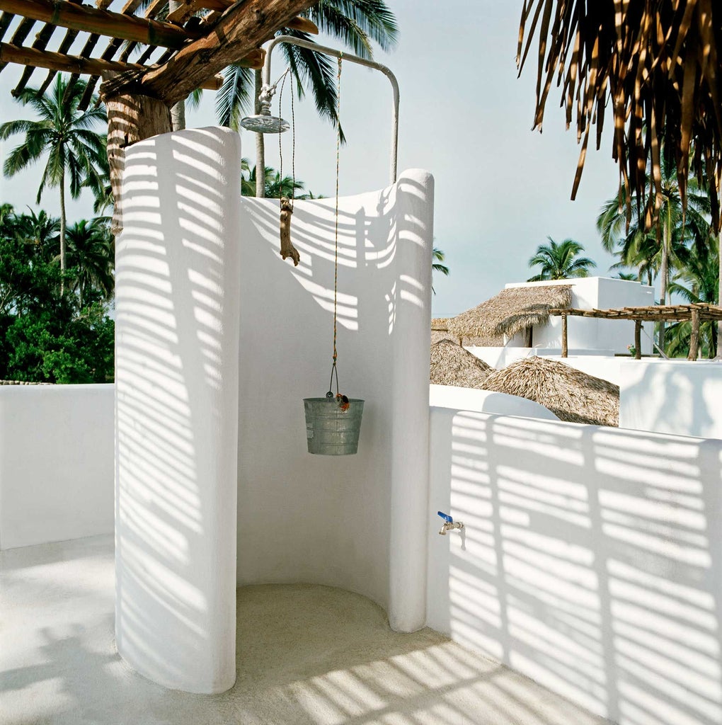 Luxurious beachfront hotel with white stucco architecture, palm trees, and turquoise waters of Mexican coastline, showcasing elegant tropical resort design