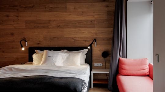 Sleek deluxe hotel room with minimalist Icelandic design, floor-to-ceiling windows revealing dramatic urban landscape, modern furnishings in neutral tones