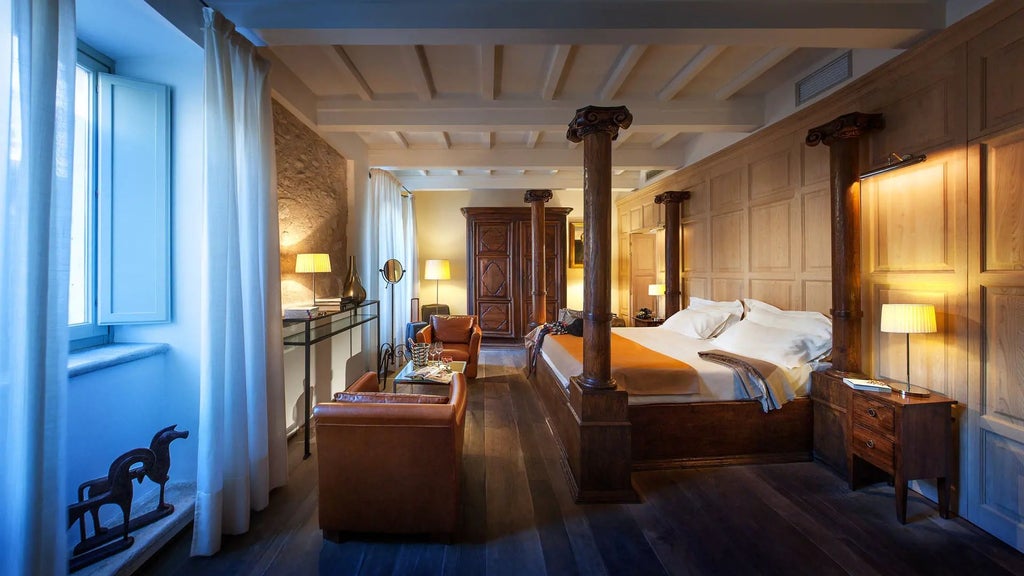 Elegant stone-walled suite with plush king bed, antique wooden furnishings, and soft ambient lighting in historic Palazzo Seneca, Umbria, Italy