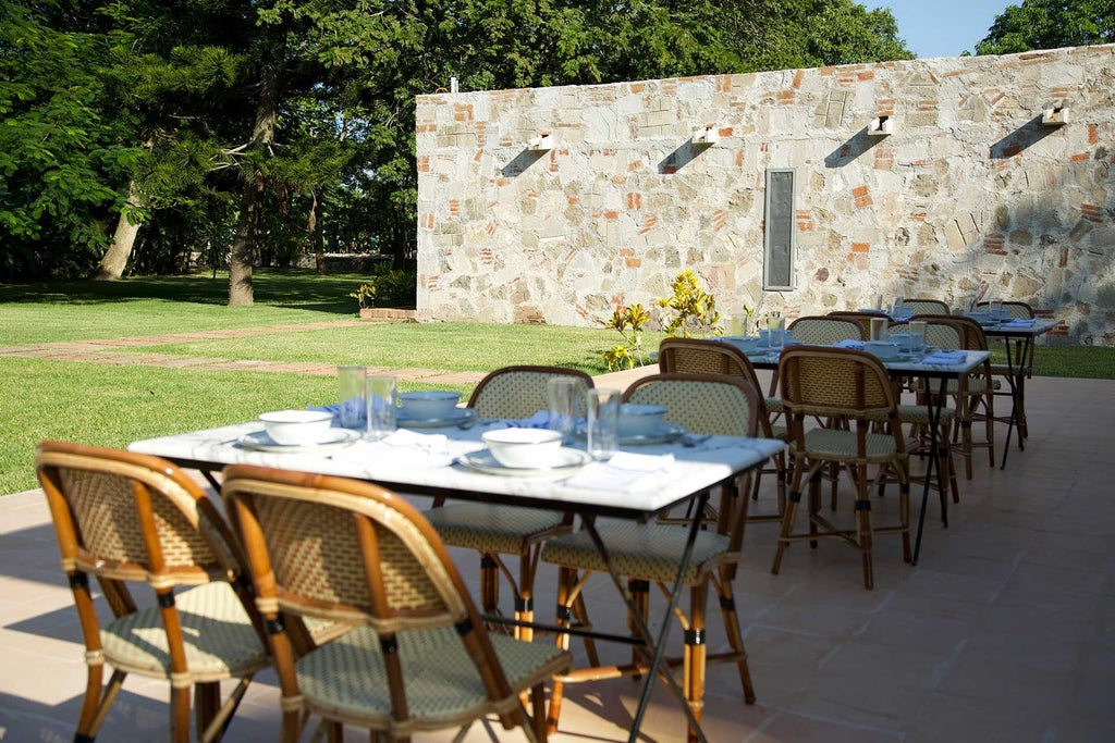 Elegant colonial-style luxury hotel with white facade, lush tropical gardens, and vibrant red bougainvillea framing traditional Mexican architectural details.