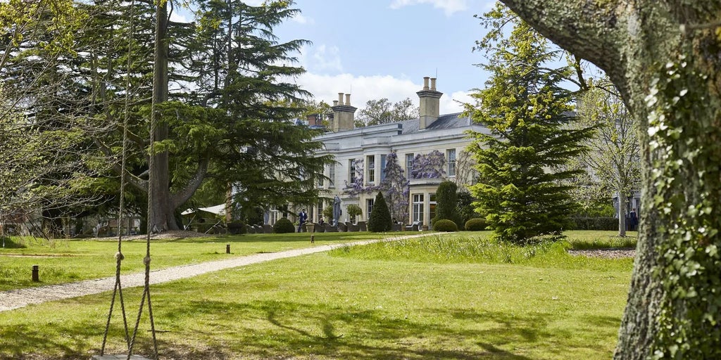 Luxurious countryside retreat nestled in New Forest, UK: rustic-chic timber exterior, manicured gardens, and elegant architectural design of Lime Wood Hotel