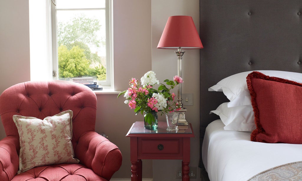 Luxurious modern hotel bedroom with crisp white linens, soft grey headboard, elegant wooden floors, and minimalist design in a peaceful UK setting