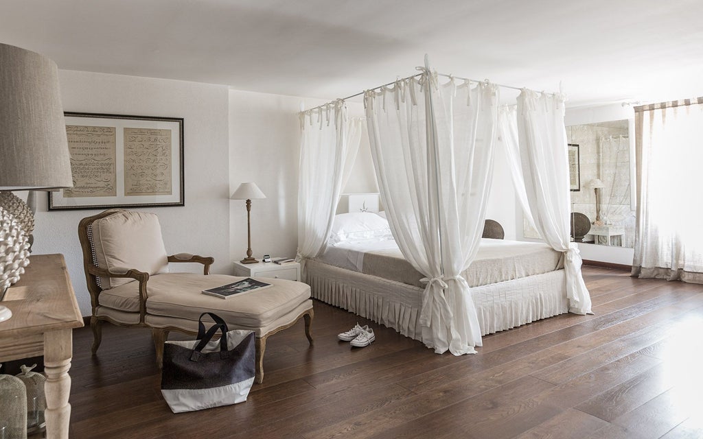 Elegant Italian hotel room with vintage furnishings, soft neutral tones, antique wooden furniture, and large arched windows overlooking a serene landscape