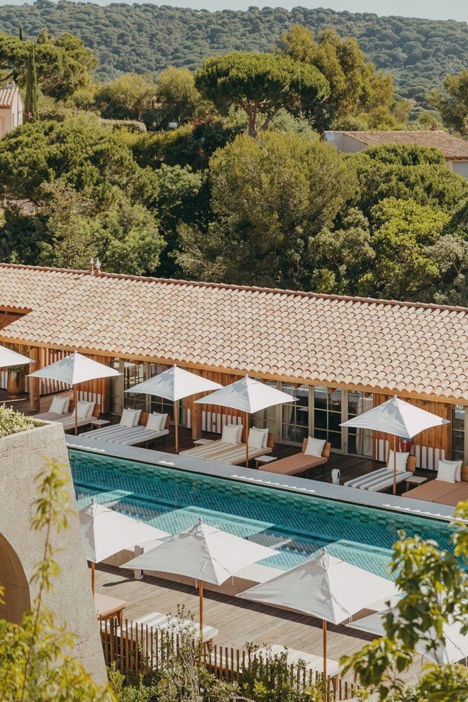 Elegant hilltop hotel overlooking Mediterranean, featuring infinity pools, modern glass architecture, and lush gardens in Saint-Tropez