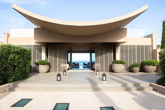 Cliffside luxury hotel overlooking Mediterranean Sea, with infinity pool, modern white architecture, and lush gardens in French Riviera