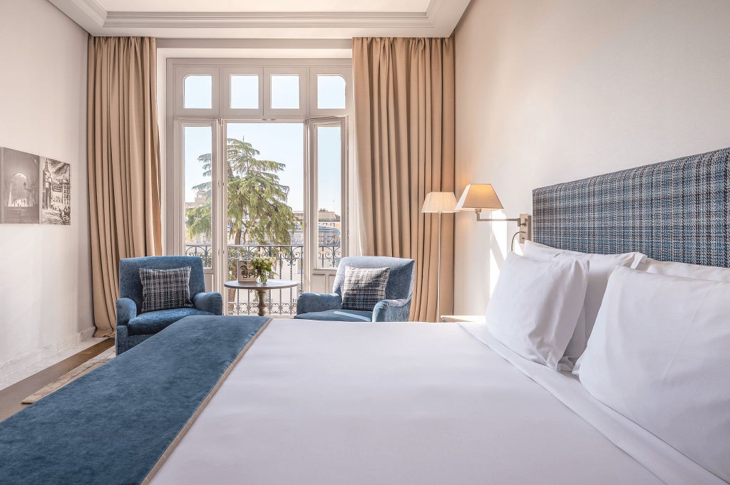 Elegant deluxe hotel room with panoramic palace views, plush white bedding, modern minimalist design, and soft natural lighting in Madrid