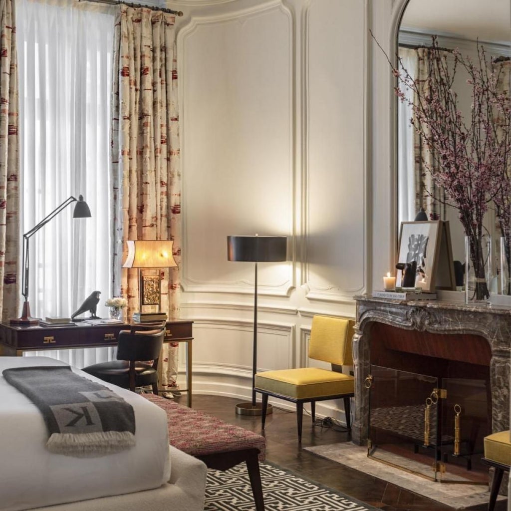 Elegant Parisian hotel interior with plush white chairs, marble fireplace, and rich blue walls showcasing refined luxury design in classic French style