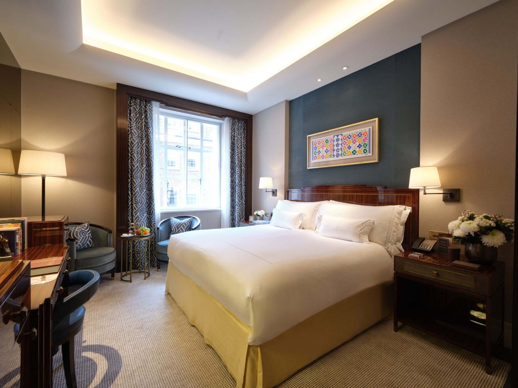 Elegant classic room at scenset hotel with plush king bed, cream walls, dark wood furnishings, and soft ambient lighting in luxurious Mayfair style