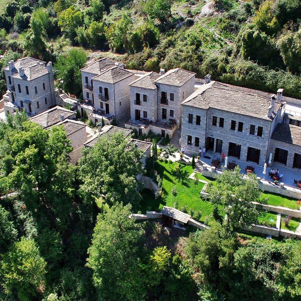 Luxury stone-built mountain resort with panoramic balconies nestled in misty Greek peaks, showcasing traditional architecture and lush scenery