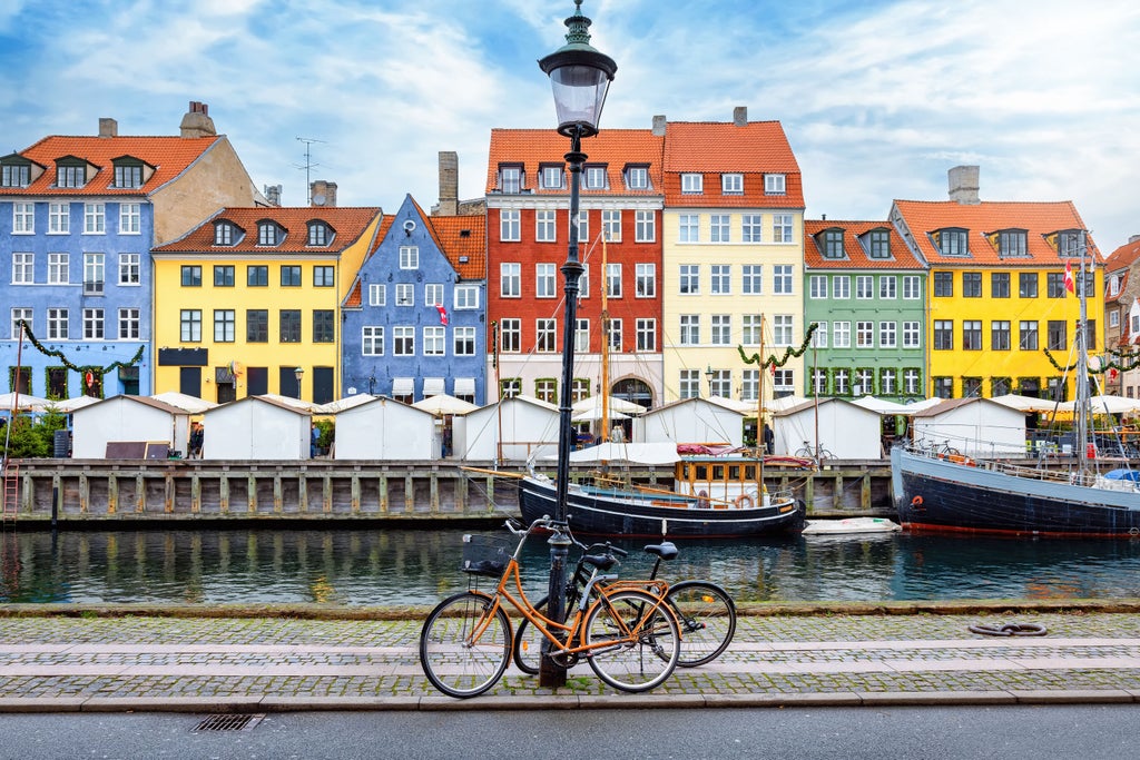 Elegant cobblestone street in Copenhagen's historic district with traditional colorful townhouses and bicycles under cloudy skies