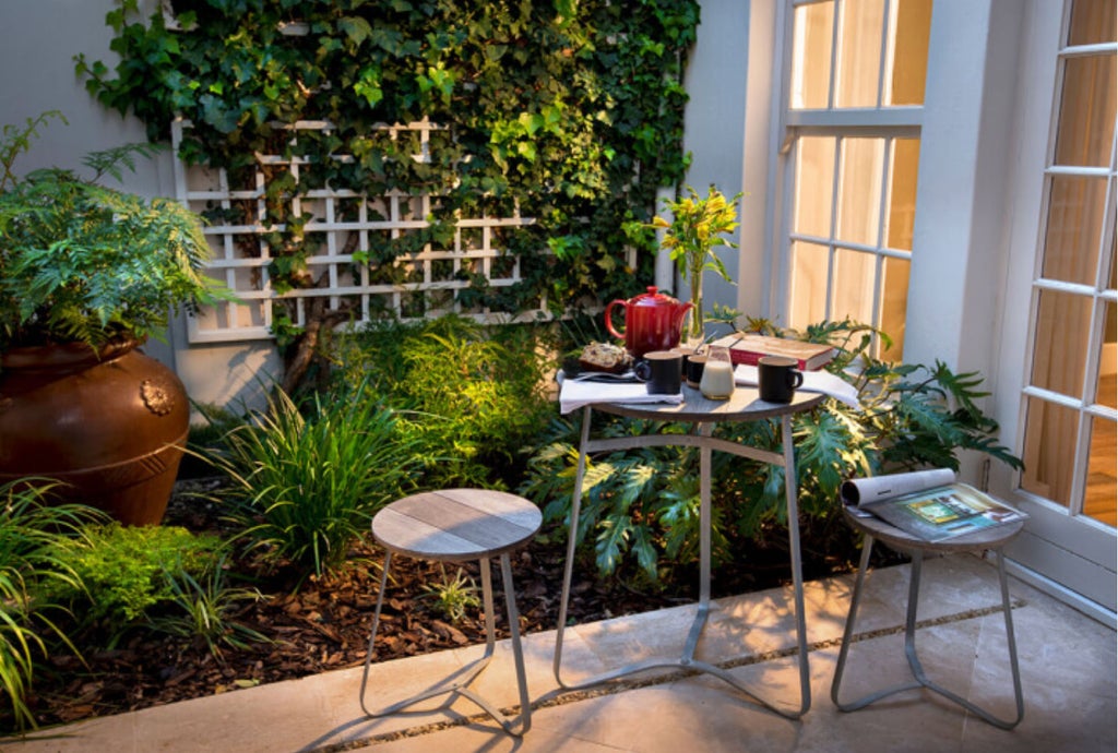 Elegant boutique hotel exterior with modern Cape Dutch architecture, featuring white walls, wooden accents and lush garden landscaping