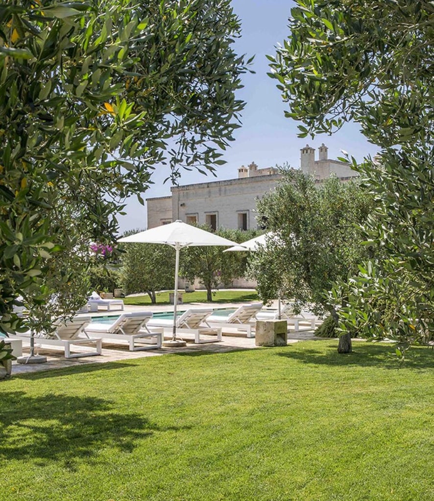 Elegant Mediterranean hotel suite with arched stone walls, draped canopy bed, antique furniture and warm ambient lighting