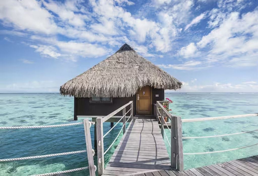 Luxurious overwater bungalow with glass floor panels, private deck, and panoramic lagoon views at Hilton Moorea in French Polynesia