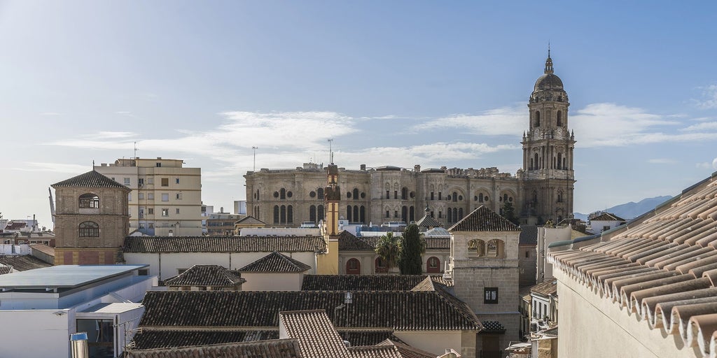 Elegant 18th century boutique hotel exterior with ornate stone facade, wrought iron balconies and arched windows in historic Málaga