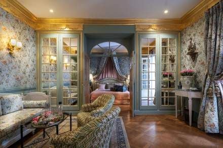 Elegant French Provençal suite with private terrace, soft lavender tones, antique furnishings, and large windows overlooking lush garden landscape