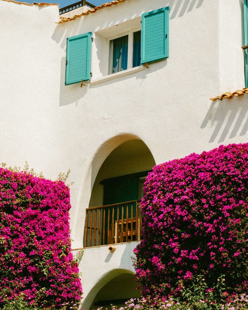 Mediterranean luxury resort with white-washed architecture, arched windows and private balconies overlooking turquoise sea and manicured gardens