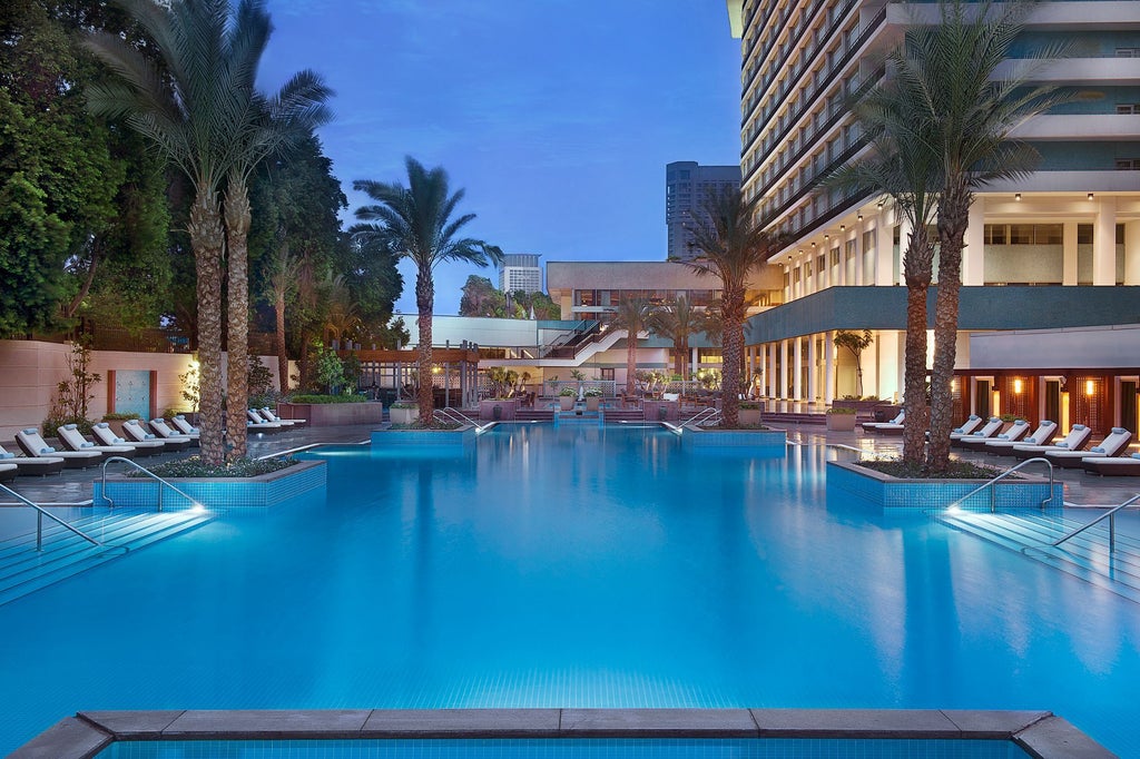 Luxurious hotel facade of The Nile Ritz Carlton with palm trees, ornate architecture and fountains overlooking the Nile River in Cairo