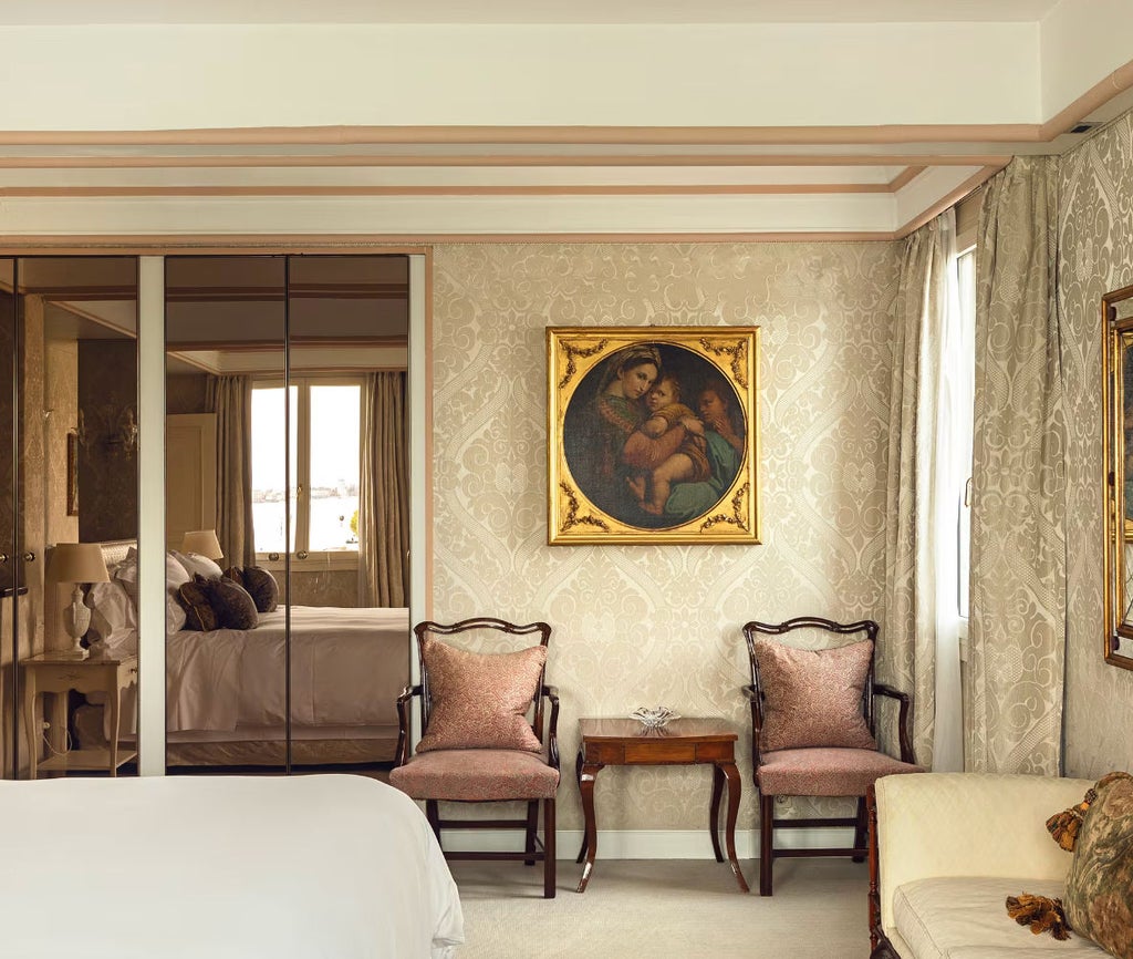 Opulent hotel suite with canal views; marble floors, Venetian décor, chandeliers, and private balcony overlooking the Venice lagoon