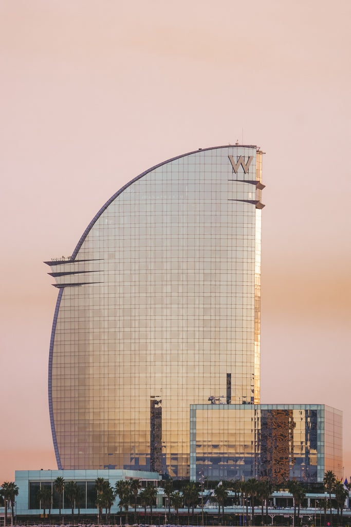 Gothic and modern Barcelona cityscape at sunset, featuring Sagrada Familia's iconic spires against a warm golden sky and luxurious urban architecture