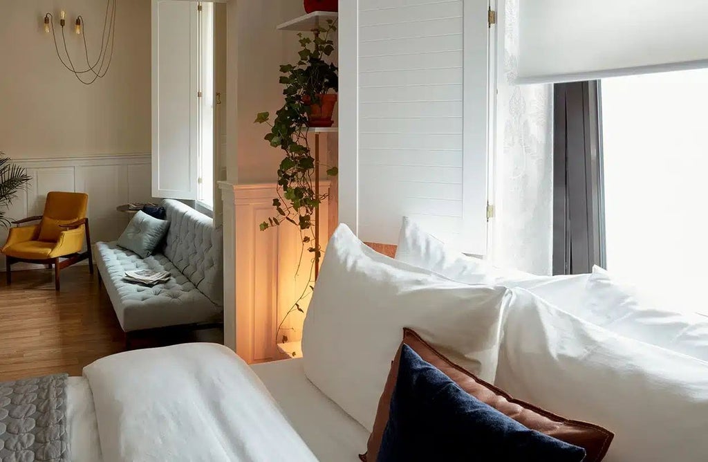 Spacious, modern hotel room with minimalist design, plush white bedding, sleek wooden furniture, and large window overlooking urban scenery in Berlin's vibrant Ku'damm district