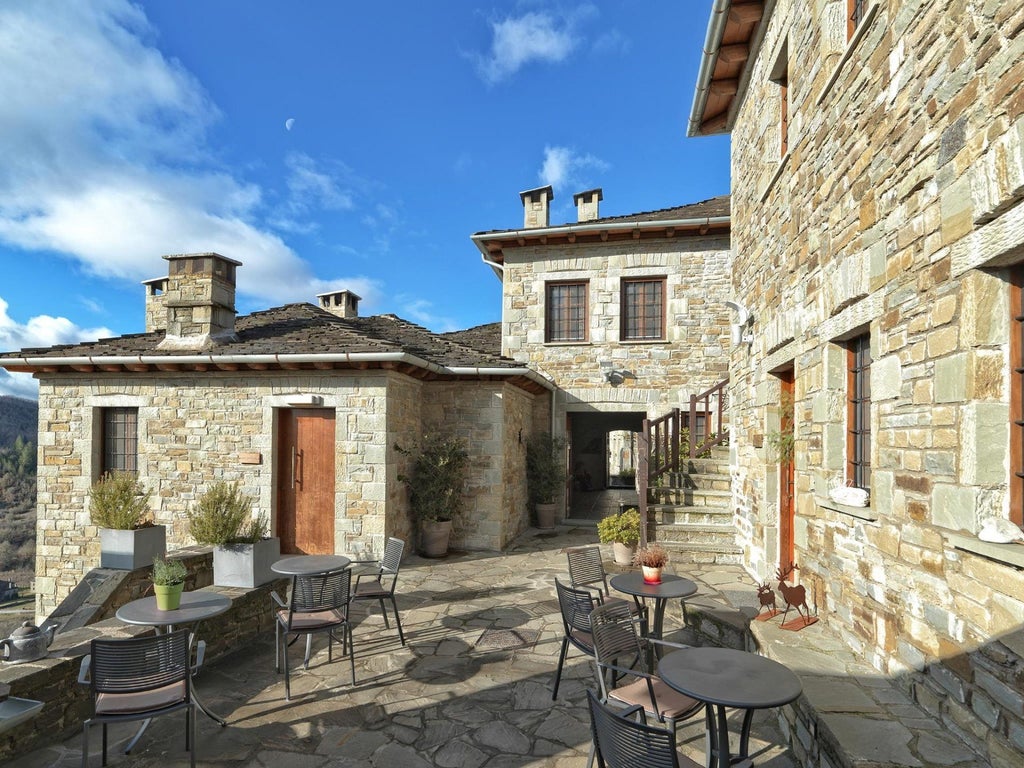 Luxurious stone villa with Mediterranean terrace overlooking azure Aegean waters, nestled in a serene Greek landscape with elegant architectural details