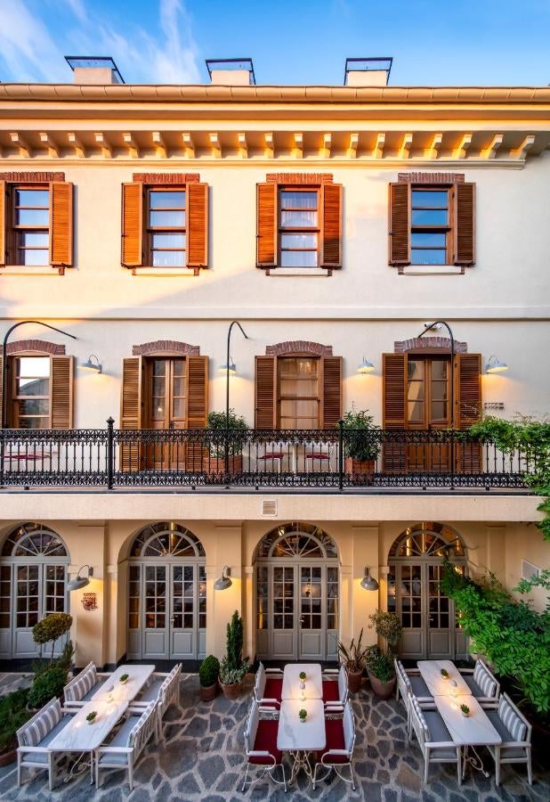 Historic stone hotel with elegant arched windows and wooden balconies set against rocky mountains, featuring a traditional Turkish facade