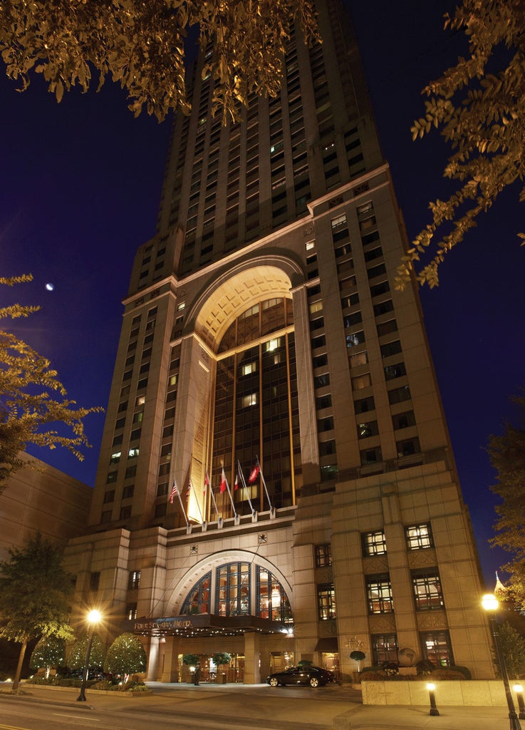 Elegant glass skyscraper hotel with neoclassical facade, featuring a grand entrance with valet service and manicured landscaping in Atlanta