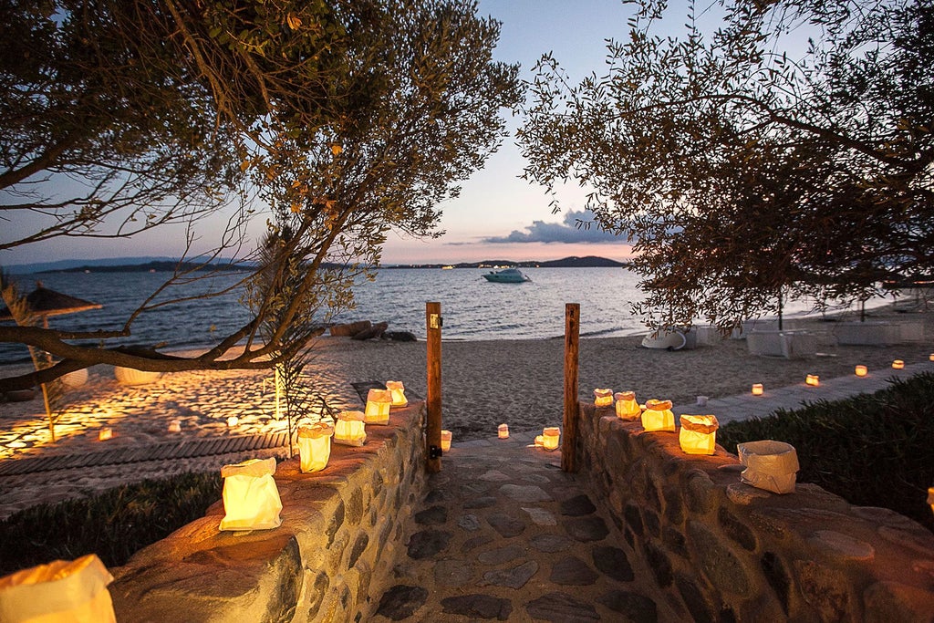 Luxurious seafront hotel with white and blue architecture nestled against turquoise Aegean waters, featuring elegant balconies and pristine coastal landscape in Greece