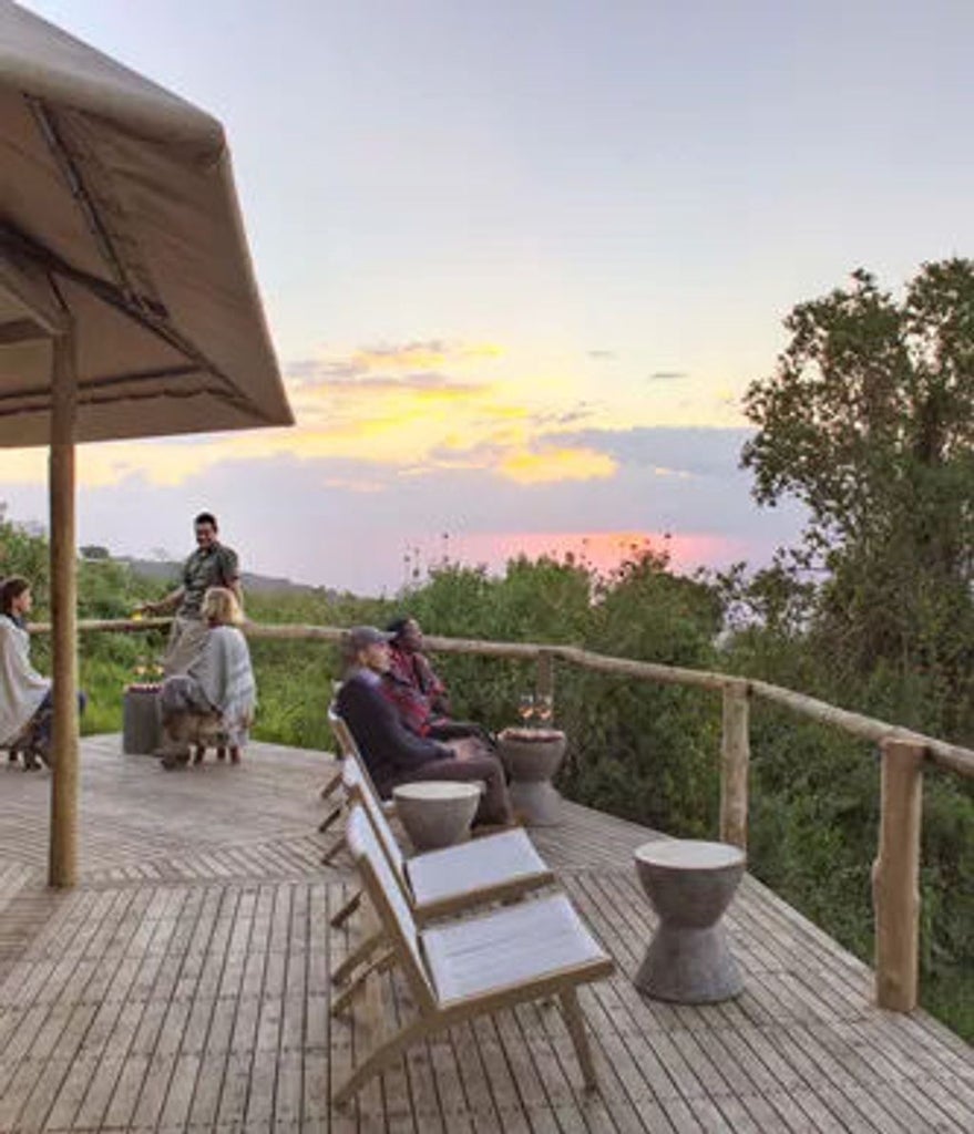 Luxurious safari tent perched on wooden platform overlooking Ngorongoro Crater, with canvas walls and elegant outdoor deck furniture