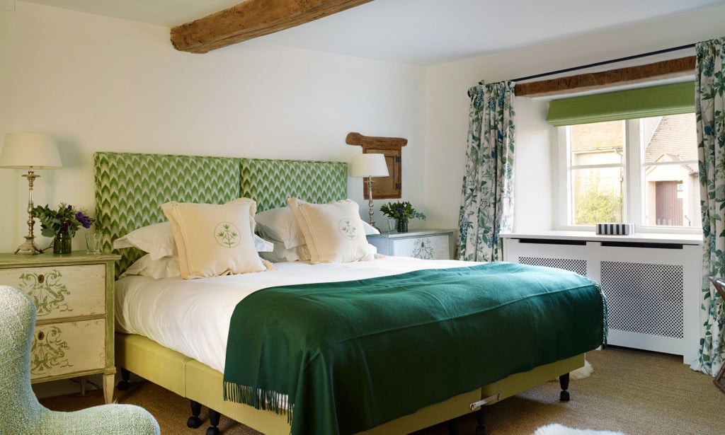 Luxurious vintage hotel room with exposed stone walls, elegant antique furnishings, soft thyme-green textiles, and warm ambient lighting creating intimate charm