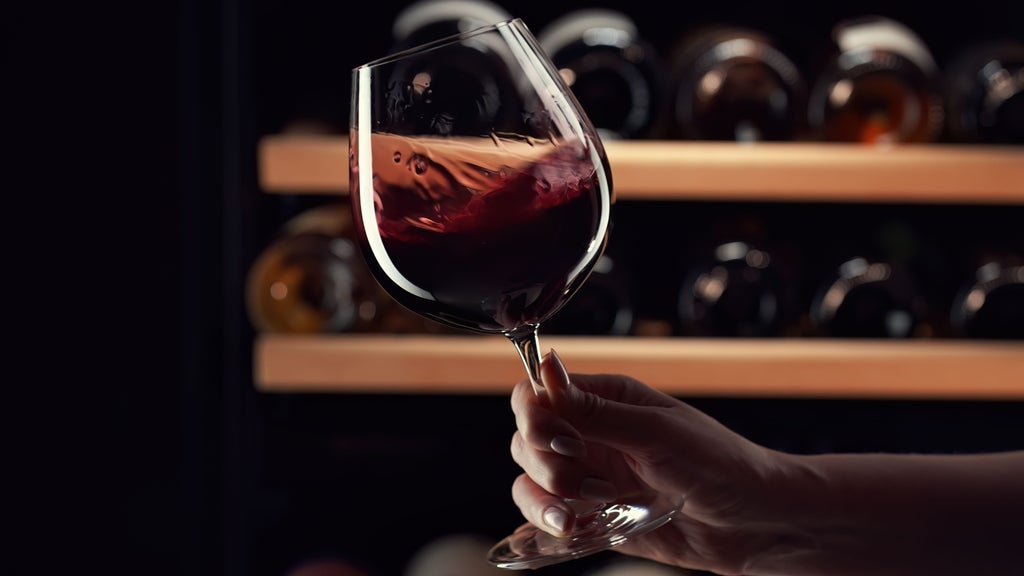 Two elegant wine glasses and artisanal chocolates arranged on rustic wooden table with Swiss Alps mountain vista through window