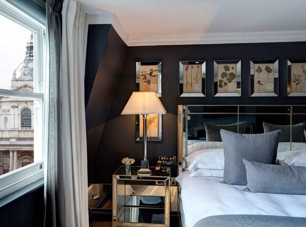 Elegant superior hotel room with plush king-sized bed, soft neutral tones, modern minimalist decor, and large window offering city skyline view in United Kingdom