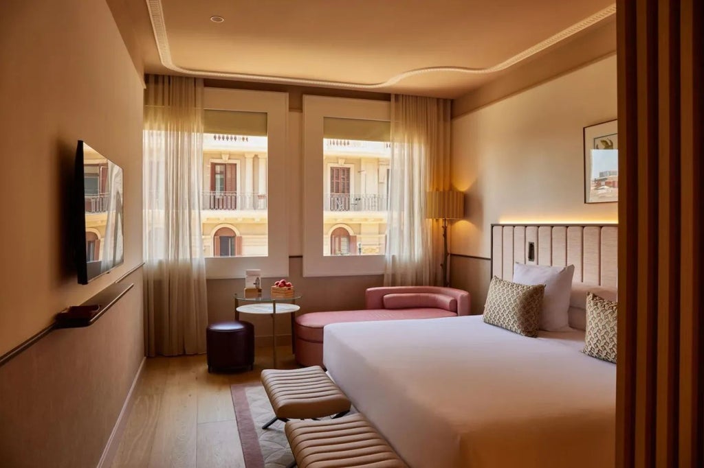 Elegant deluxe hotel room with modern decor, floor-to-ceiling windows overlooking city, plush king bed, and sophisticated marble bathroom in Spain's Grand Hotel Central