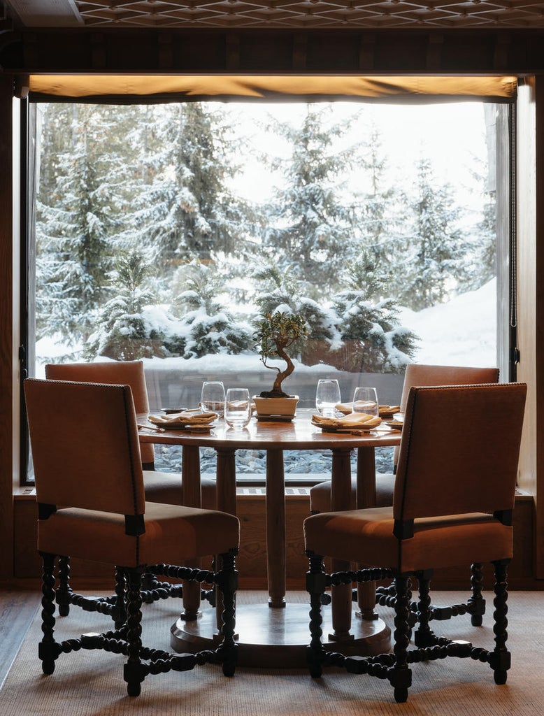 Snow-covered luxury ski resort with elegant wood and stone facade nestled in French Alps, surrounded by snow-dusted evergreens