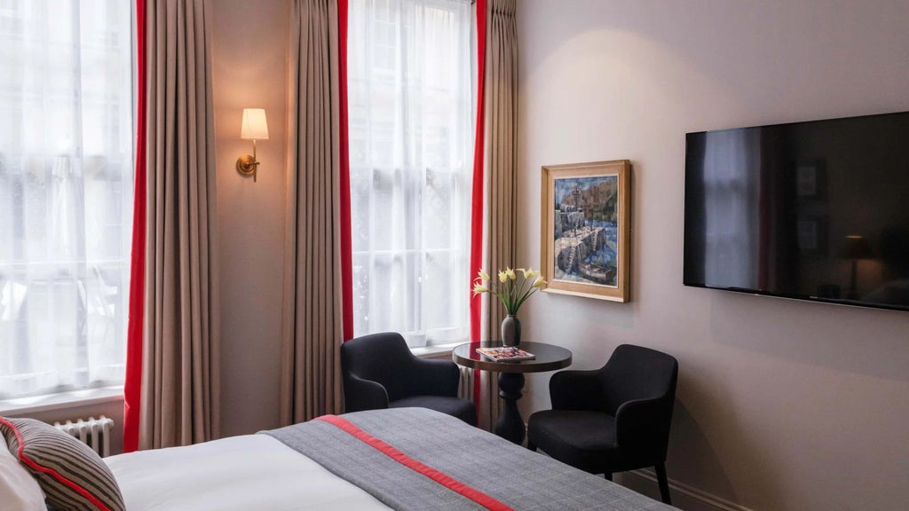 Elegant traditional hotel room with mahogany furnishings, plush cream bedding, and vintage artwork showcasing refined British hospitality in a historic Oxford setting