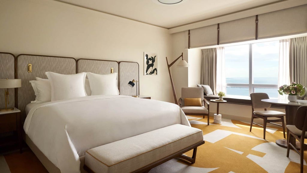 Luxurious Four Seasons bay-view hotel room in Miami with modern decor, floor-to-ceiling windows overlooking sparkling blue waters and city skyline