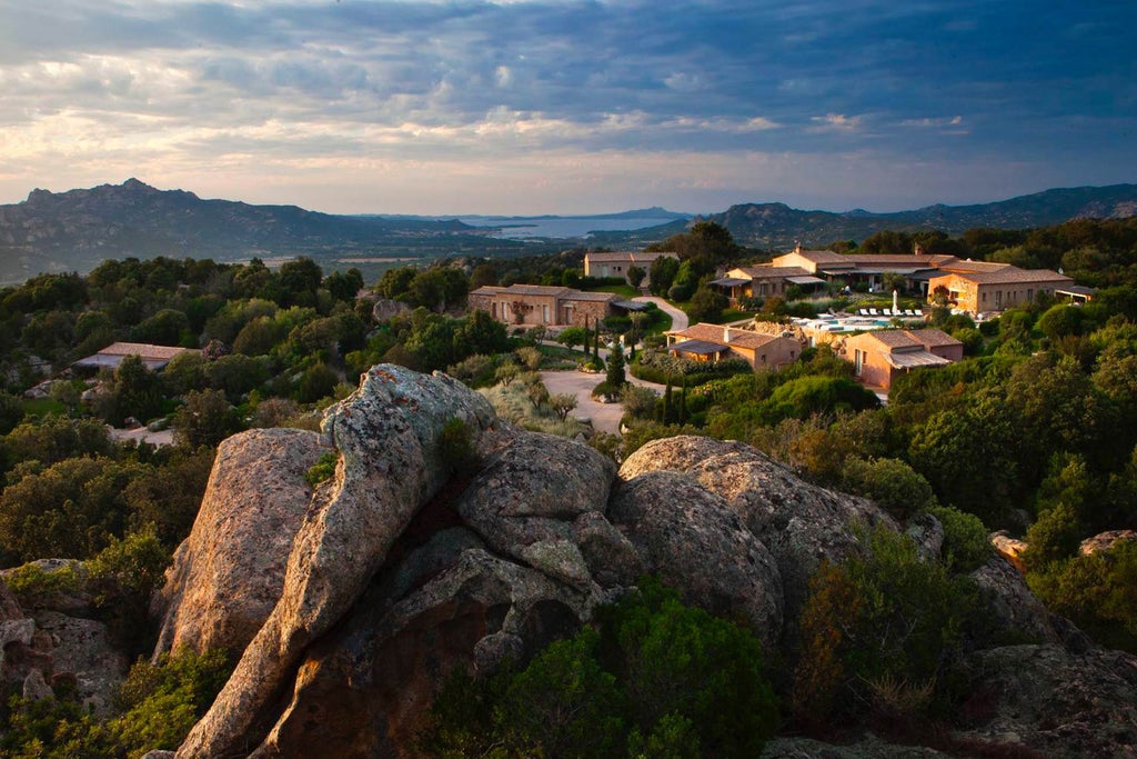 Luxury mountain resort with infinity pool overlooking rolling Sardinian hills, stone architecture blending into natural landscape