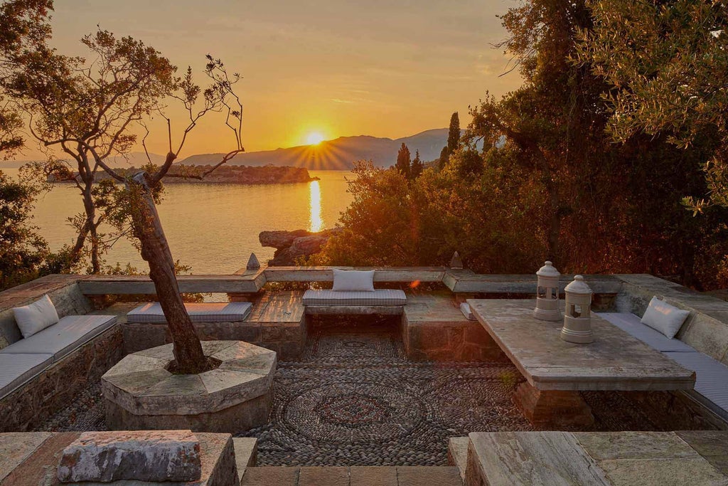 Elegant stone villa with terracotta roof overlooking azure Aegean Sea, surrounded by lush Mediterranean landscape and traditional Greek architectural design