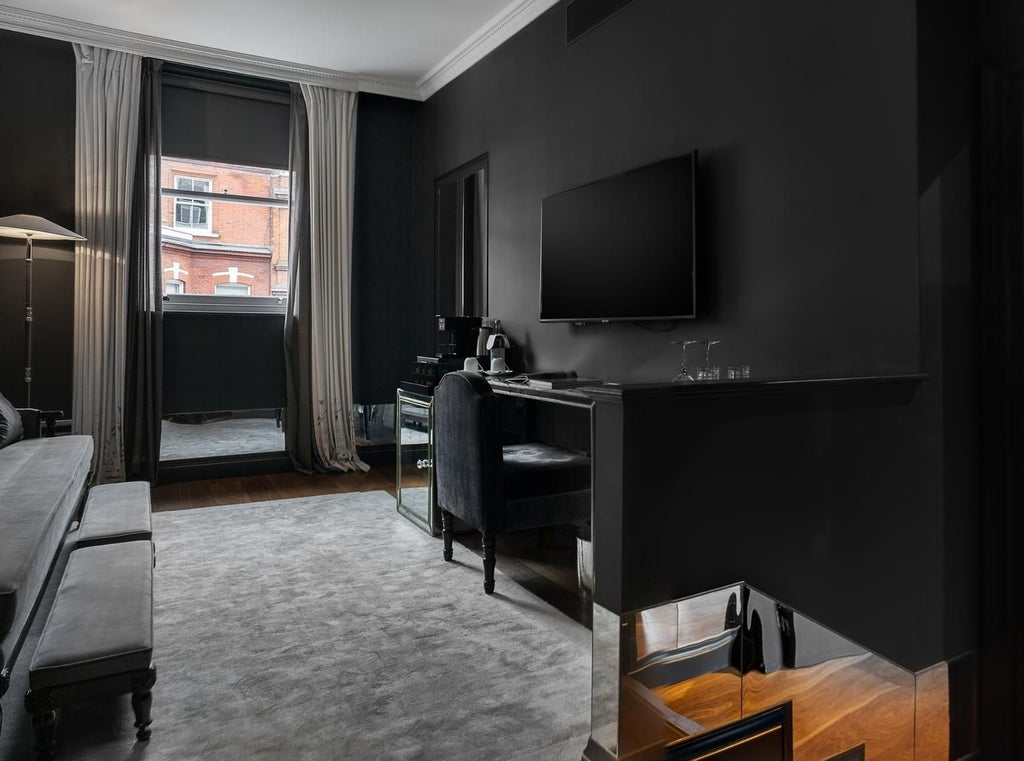 Luxurious executive suite with elegant king bed, plush neutral furnishings, city skyline view, and modern minimalist design in a prestigious UK hotel room