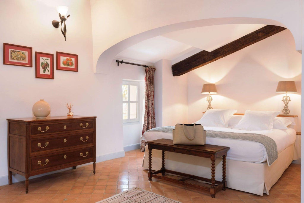 Elegant French country hotel room with soft beige linens, antique wooden furniture, and delicate stone walls at a historic monastery retreat