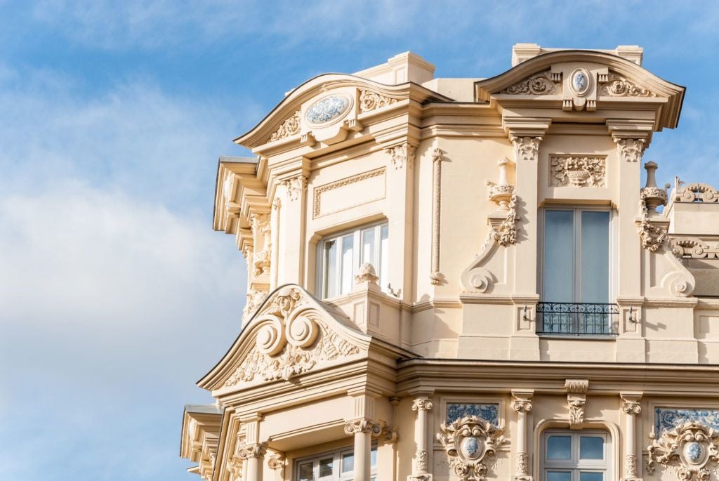 Luxurious boutique hotel with elegant white facade, ornate balconies, and classic Spanish architectural details nestled in a vibrant urban setting in Madrid.